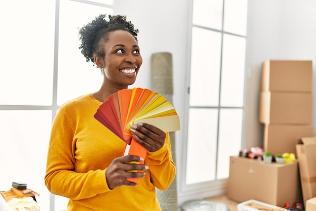 Donna afroamericana sorridente fiducioso che tiene il test del colore nella nuova casa