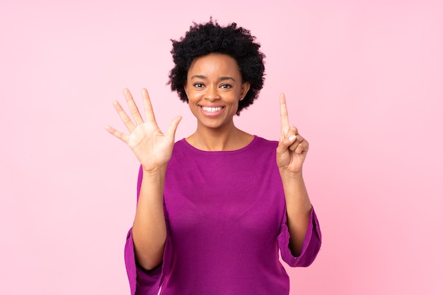 Donna afroamericana sul rosa isolato che conta sei con le dita