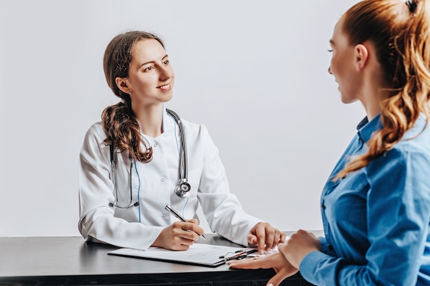 Donna al medico alla reception per controllare la salute al tavolo su uno spazio bianco isolato