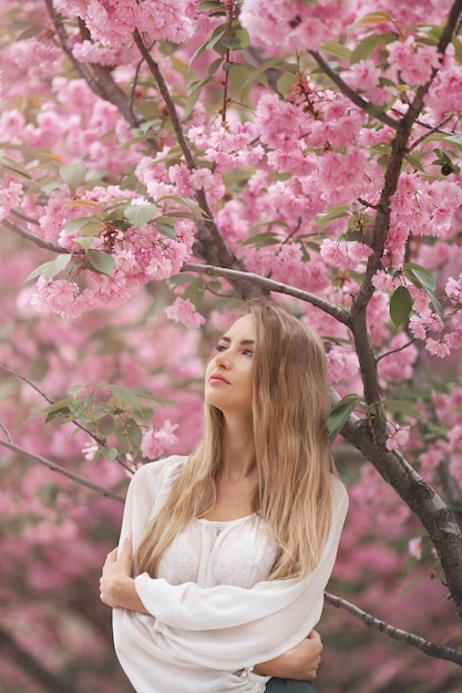 Donna all'albero sbocciante di Sakura sulla natura