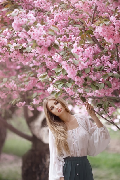 Donna all'albero sbocciante di Sakura sulla natura