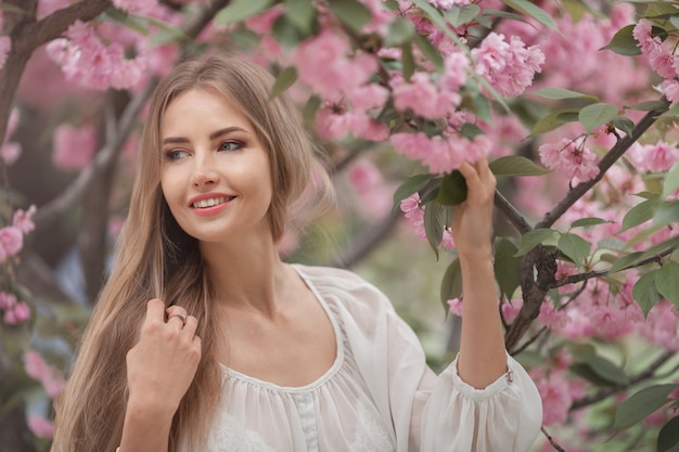 Donna all'albero sbocciante di Sakura sulla natura