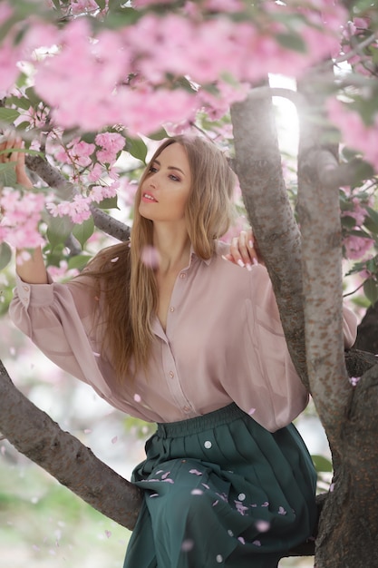 Donna all'albero sbocciante di Sakura sulla natura