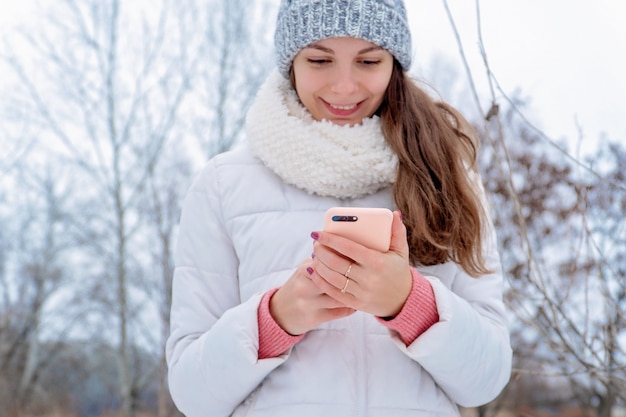 Donna all&#39;aperto della ragazza che usando il blogger online di caso di rosa del cappello bianco freddo della neve di inverno del telefono