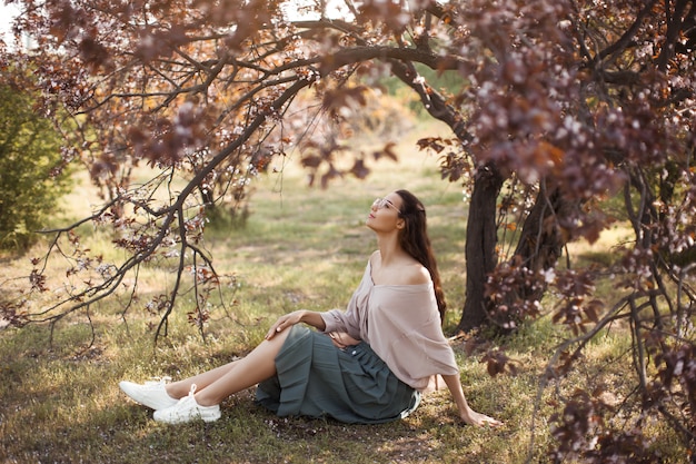 Donna all'aperto nel parco vicino all'albero del fiore della primavera