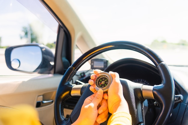 Donna all'interno di un'auto e utilizzando la bussola per navigare durante la guida dell'auto