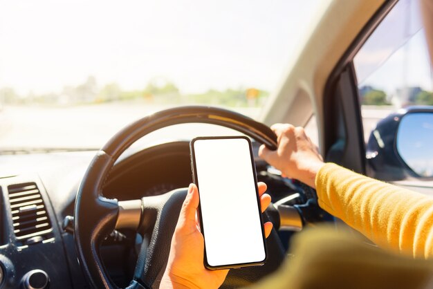 Donna all'interno di un'auto e utilizzando una mano che tiene lo schermo vuoto dello smartphone mobile mentre si guida l'auto