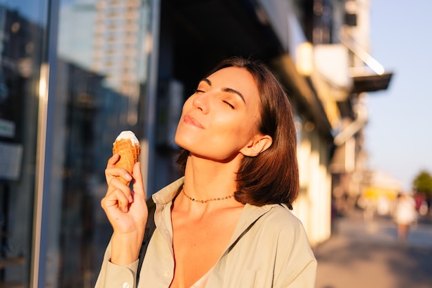 Donna all'ora del tramonto estivo con cono gelato in città street