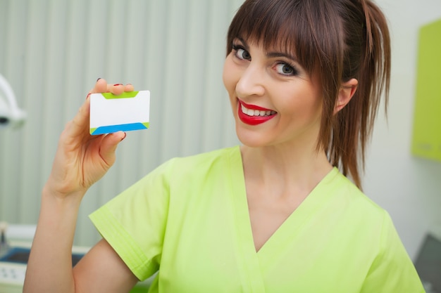 Donna alla clinica dentale che tiene i biglietti da visita in bianco