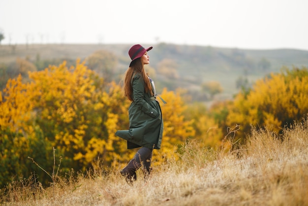 Donna alla moda che gode del tempo di autunno nel prato