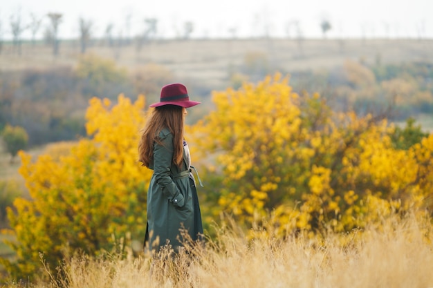 Donna alla moda che gode del tempo di autunno nel prato