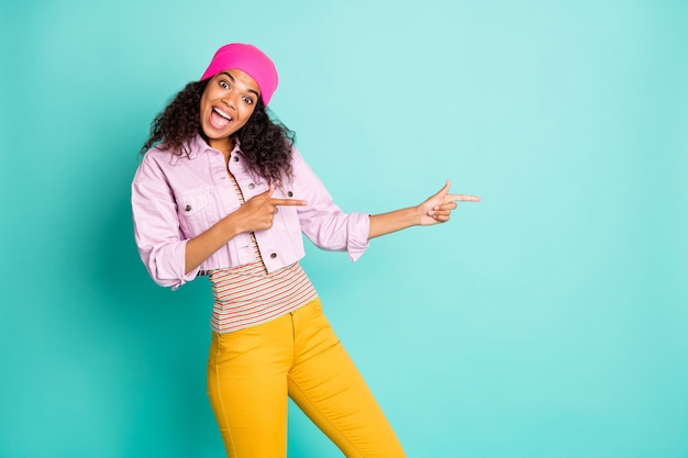 Donna alla moda con acconciatura afro in posa contro il muro blu