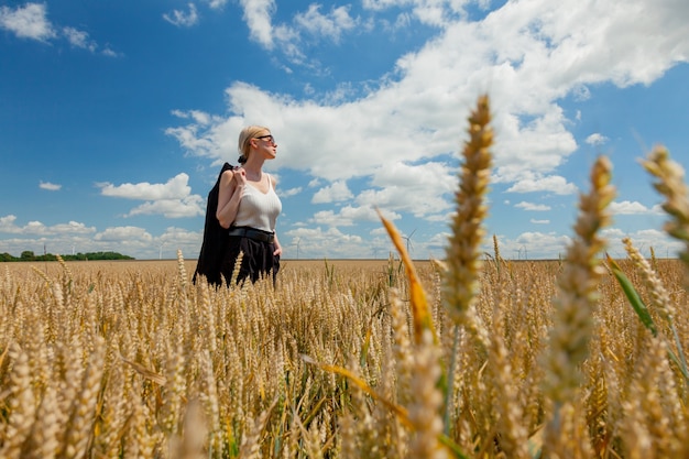 Donna alla moda con capelli biondi che posano in vestiti convenzionali nel campo di grano wheat