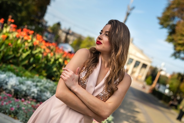 Donna alla moda con il trucco che cammina per la strada della città, goditi la giornata estiva.