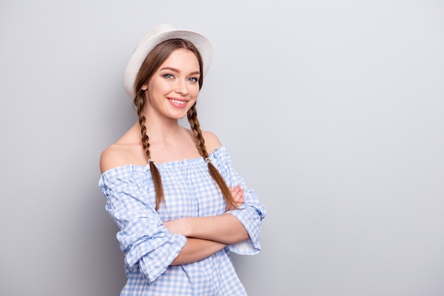 Donna alla moda con trecce e cappello in posa contro il muro bianco