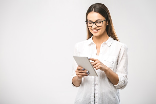 Donna alla moda fiduciosa abbastanza affascinante in camicia classica con tablet nelle mani