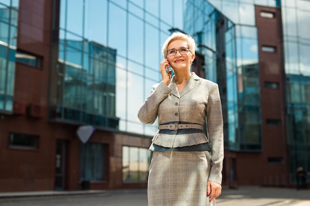 Donna alla moda in un vestito e occhiali parlando sullo smartphone