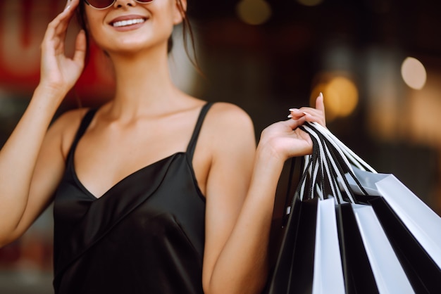 Donna alla moda vestita di un abito nero con borse della spesa.