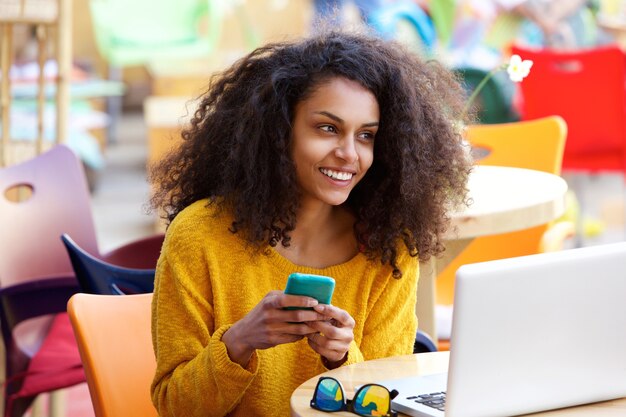 Donna allegra al caffè all&#39;aperto con il telefono cellulare