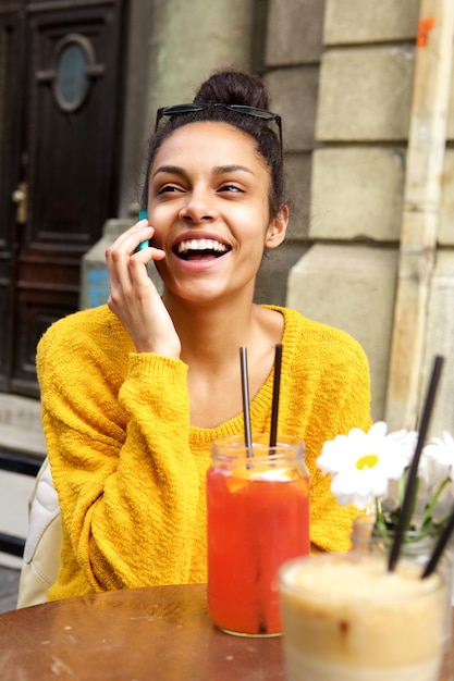 Donna allegra al caffè all&#39;aperto utilizzando il telefono cellulare