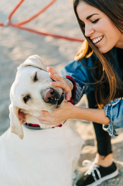 Donna allegra che accarezza il cane nel parco giochi durante il tramonto