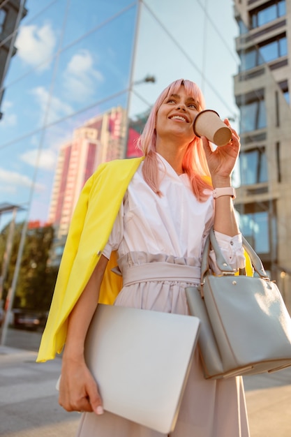 Donna allegra che beve caffè per strada