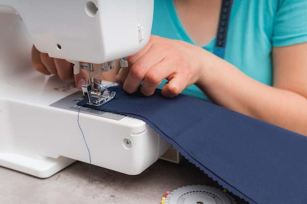 Donna allegra che cuce mentre è seduta al suo posto di lavoro nel laboratorio di moda