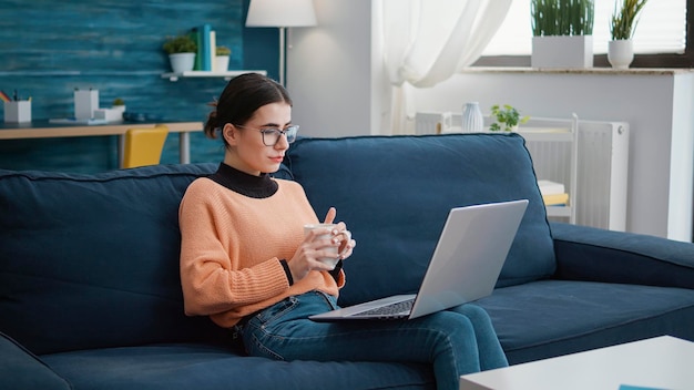 Donna allegra che frequenta la lezione scolastica online sul laptop, utilizzando la conferenza remota per apprendere conoscenze e fare ricerche sull'assegnazione del progetto di classe. Giovane adulto sorridente e guardando il corso.