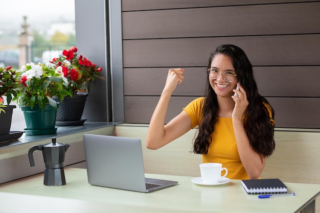 Donna allegra che lavora al computer portatile nella caffetteria