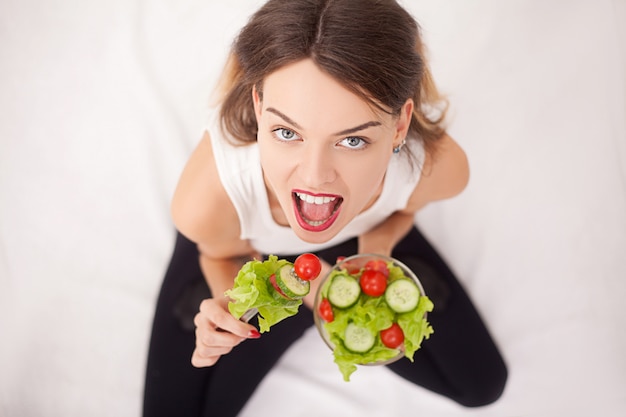 Donna allegra che mangia insalata di verdure