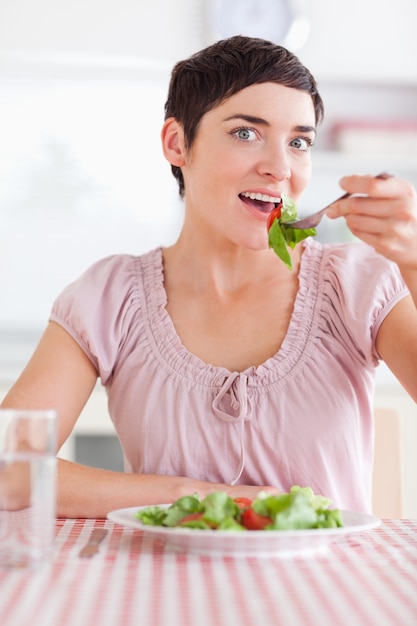 Donna allegra che mangia insalata