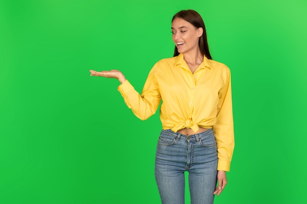 Donna allegra che tiene un oggetto invisibile a portata di mano su sfondo verde