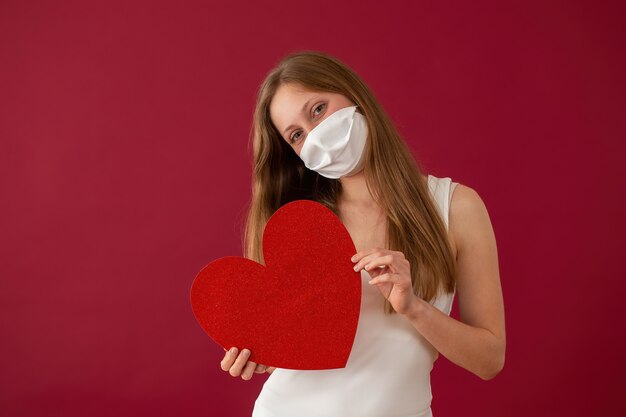 Donna allegra con maschera facciale che mostra cuore rosso dalla vista frontale.