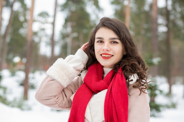 Donna allegra con rossetto rosso in posa in inverno nevoso. Spazio vuoto