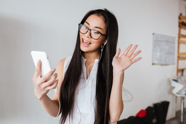 Donna allegra e cuffie che fanno videochiamata facendo uso del telefono cellulare