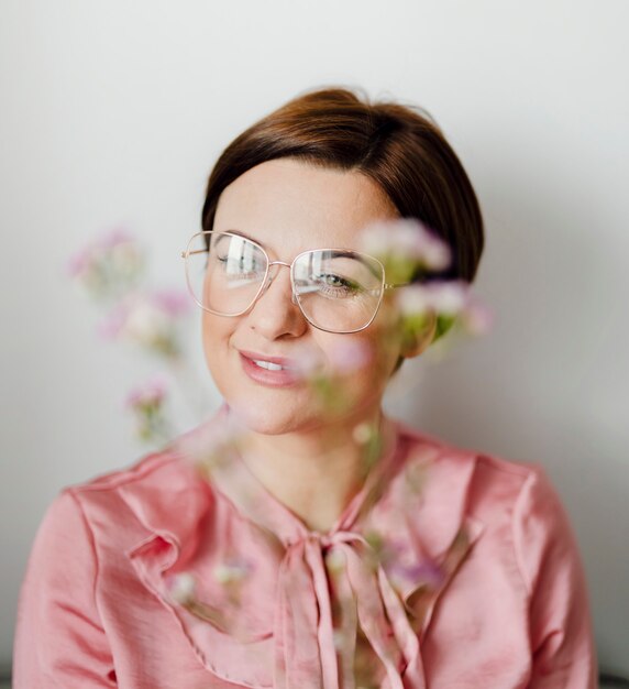 Donna allegra in una camicia rosa che tiene fiori di cera