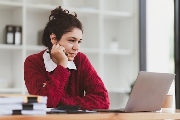 Donna americana che sembra stressata durante l'utilizzo del laptop con documento finanziario sul tavolo Donna lavora da casa