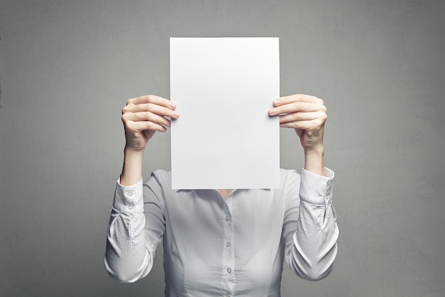Donna anonima che copre il viso con un foglio di carta