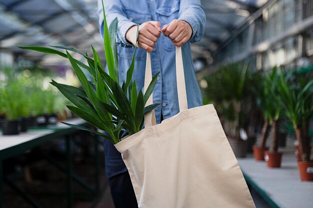 Donna anonima che tiene in mano una borsa riutilizzabile ecologica con yucca in essoSerra sullo sfondo