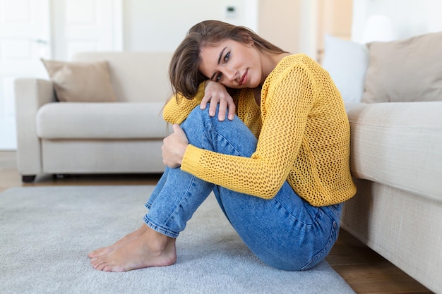 Donna ansiosa e preoccupata seduta sul divano a casa La donna confusa frustrata sente problemi infelici nella vita personale, la lite si rompe con il fidanzato e il concetto di gravidanza inaspettato