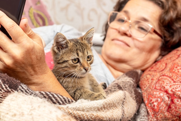 Donna anziana a letto con telefono e gattino, amore per gli animali