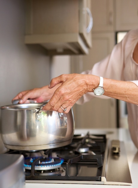 Donna anziana acqua bollente in pentola sul fornello
