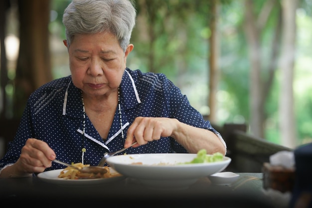 Donna anziana anziana che mangia cibo sulla terrazza stile di vita maturo di pensionamento