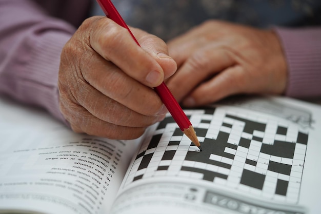 Donna anziana asiatica che gioca a sudoku puzzle game per praticare l'allenamento del cervello per la prevenzione della demenza malattia di Alzheimer
