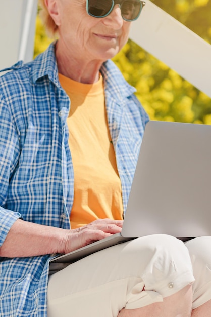 Donna anziana autentica che usa il portatile per l'istruzione a distanza all'aperto