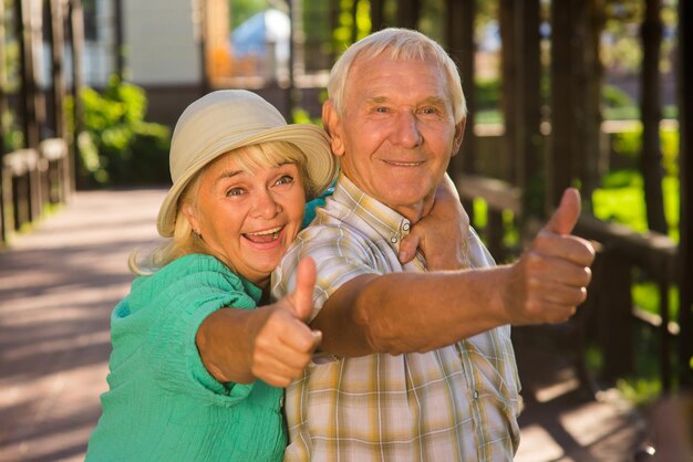 Donna anziana che abbraccia uomo coppia senior che mostra i pollici in su cuori amorevoli non si stancano molti anni sp