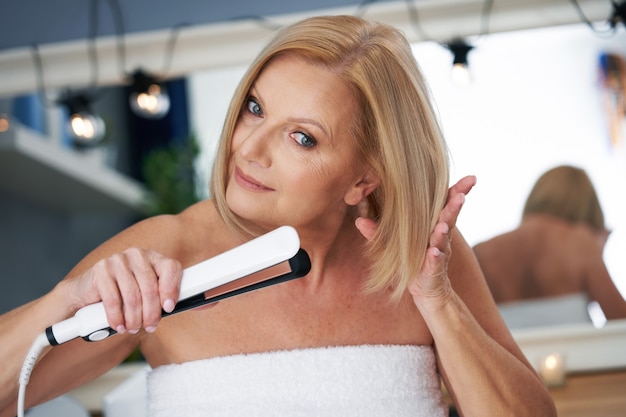 donna anziana che asciuga i capelli in bagno