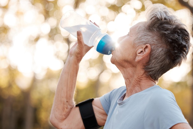 Donna anziana che beve acqua potabile e allenamento nel parco estivo e allenamento per la salute cardio e fitness Esercizio di corsa e idratazione per anziani con interruzione dell'acqua per mente o muscoli sani del corpo