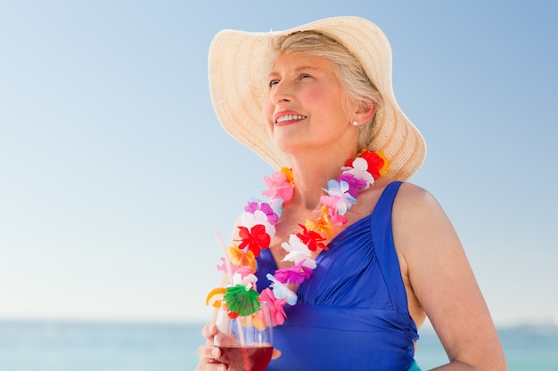 Donna anziana che beve un cocktail sulla spiaggia