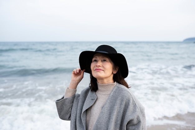 Donna anziana che cammina in riva al mare